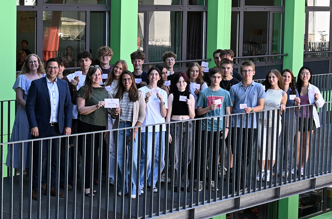Schüler und Lehrer mit Gutscheinen vor einem Schulgebäude in Österreich