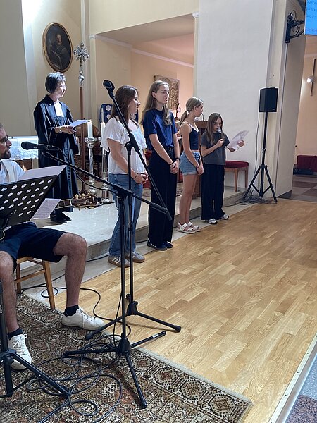 Pfarrerin mit vier Mädchen in einer Kirche, die gemeinsam singen